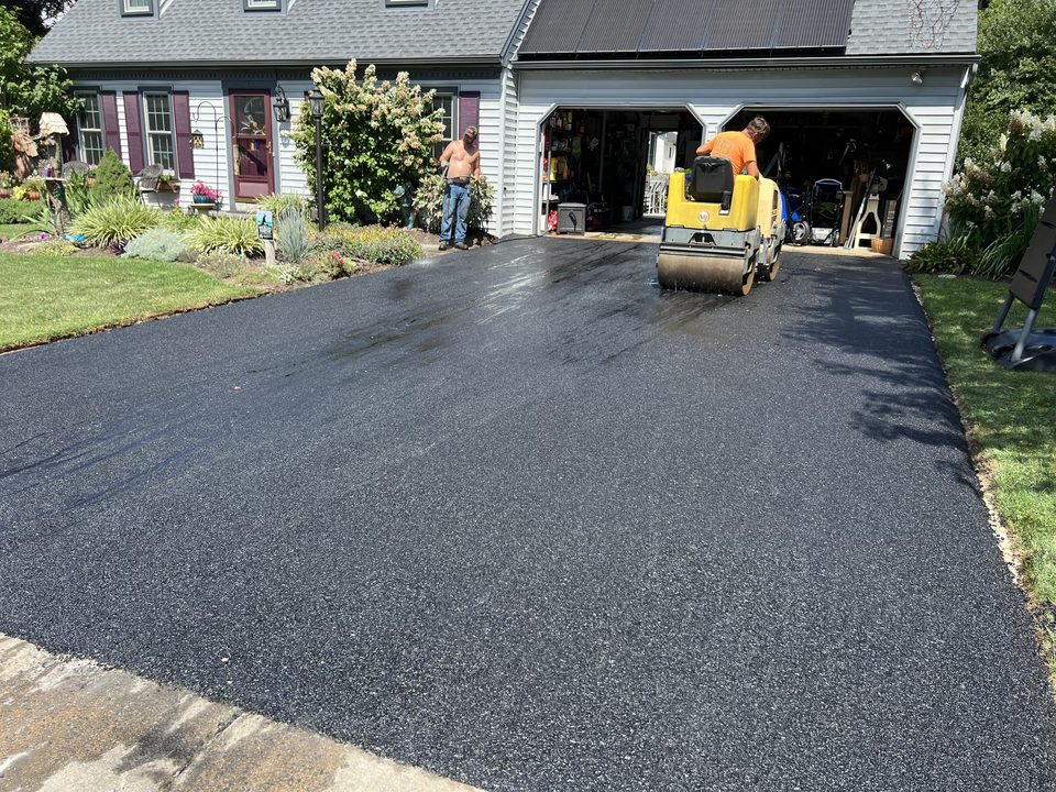 Roller compacting a new driveway by the garage