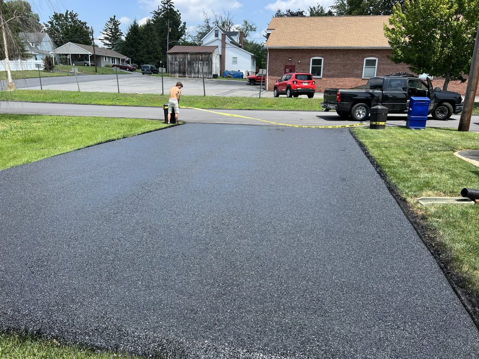 Wide residential asphalt driveway, freshly paved